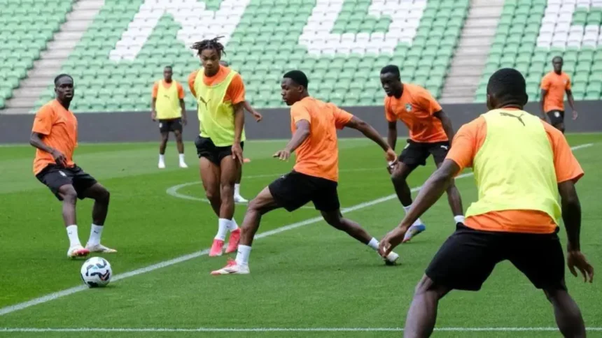 football: Joueurs ivoiriens et marocains se disputant le ballon lors d'un match amical international de haute intensité au Stade Félix Houphouët-Boigny, symbolisant les préparations stratégiques de 2026 pour la Coupe du Monde et la CAN.