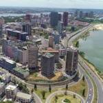 Résilience: Une vue panoramique aérienne du quartier des affaires du Plateau et de la lagune Ébrié à Abidjan en mars 2026, illustrant l'impact de la gestion stratégique des ressources des collectivités locales sur les infrastructures urbaines et le développement côtier en Côte d'Ivoire.