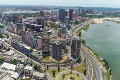 Résilience: Une vue panoramique aérienne du quartier des affaires du Plateau et de la lagune Ébrié à Abidjan en mars 2026, illustrant l'impact de la gestion stratégique des ressources des collectivités locales sur les infrastructures urbaines et le développement côtier en Côte d'Ivoire.