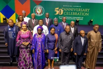 Regional Integration: Un groupe de dirigeants et de dignitaires ouest-africains lors du lancement officiel de la célébration du 50e anniversaire de la Communauté Économique des États de l'Afrique de l'Ouest (CEDEAO) à Yamoussoukro, en Côte d'Ivoire, posant devant une toile de fond commémorative verte.
