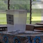 élection: Un agent de bureau de vote en Côte d'Ivoire préparant une urne, représentant le cycle des élections législatives 2025-2026 et la proclamation consécutive d'une majorité de 197 sièges pour le RHDP à l'Assemblée Nationale.
