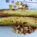 snack: Des arachides de haute qualité exposées dans un panier traditionnel tressé sur un marché local ivoirien, en mars 2026, représentant l'accent stratégique du gouvernement sur la souveraineté alimentaire et la modernisation de la chaîne de valeur agricole dans le cadre du PND 2026-2030.