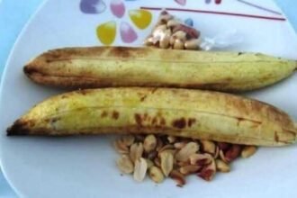 snack: Des arachides de haute qualité exposées dans un panier traditionnel tressé sur un marché local ivoirien, en mars 2026, représentant l'accent stratégique du gouvernement sur la souveraineté alimentaire et la modernisation de la chaîne de valeur agricole dans le cadre du PND 2026-2030.