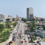 MMA: Une vue panoramique de la ligne d'horizon d'Abidjan dans le quartier du Plateau, présentant des gratte-ciels modernes et la lagune Ébrié, symbolisant la transformation économique et la croissance industrielle de la Côte d'Ivoire en 2026.