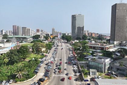 MMA: Une vue panoramique de la ligne d'horizon d'Abidjan dans le quartier du Plateau, présentant des gratte-ciels modernes et la lagune Ébrié, symbolisant la transformation économique et la croissance industrielle de la Côte d'Ivoire en 2026.