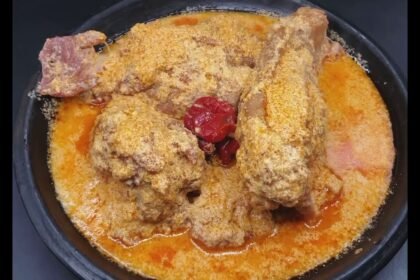 Gastronomie: Un bol appétissant de sauce pistache traditionnelle ivoirienne (soupe de graines de courge) servie avec des morceaux de viande et de poisson, représentant les riches traditions culinaires et les saveurs festives de la Côte d'Ivoire en 2026.