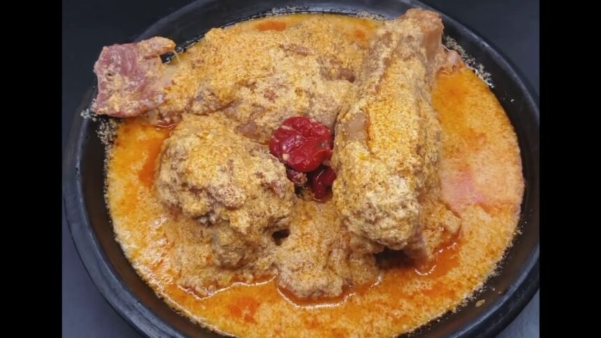 Gastronomie: Un bol appétissant de sauce pistache traditionnelle ivoirienne (soupe de graines de courge) servie avec des morceaux de viande et de poisson, représentant les riches traditions culinaires et les saveurs festives de la Côte d'Ivoire en 2026.