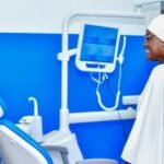 Santé Publique: Un professionnel de santé présentant un équipement dentaire moderne à une visiteuse au nouveau centre médico-scolaire ultra-moderne Mariatou Koné à Boundiali, en mars 2026, illustrant l'investissement de la Côte d'Ivoire dans la santé publique scolaire.